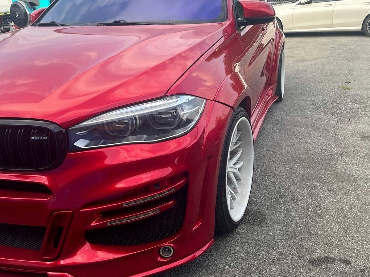 Red BMW X6M wide-body parked outside the studio