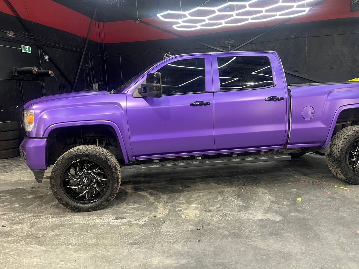 GMC Sierra pickup in satin purple wrap with off-road wheels