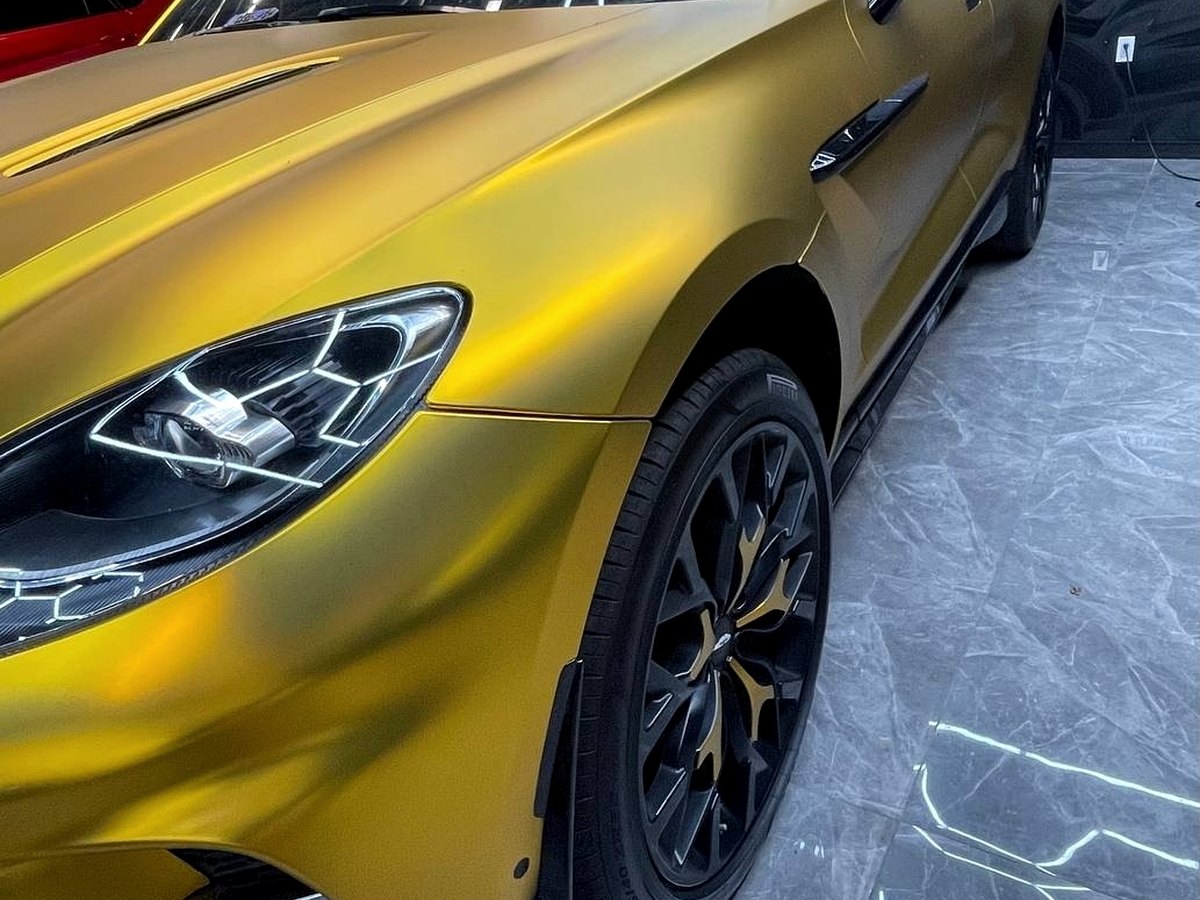 Luxury SUV in gold satin chrome wrap under honeycomb lighting